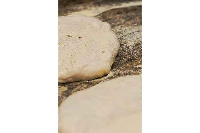 Hand-tossed pizza dough resting on a marble slab at Cavalli Pizzeria