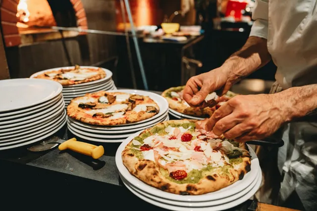 A finishing touch of fresh parmesan being added to a pizza at Cavalli Pizzeria
